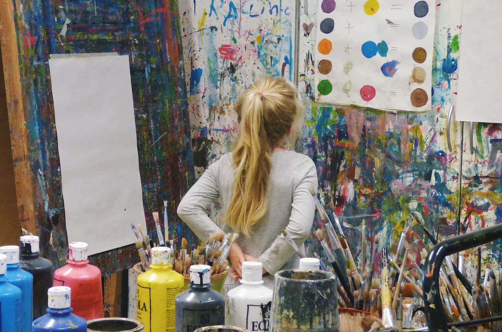 An artist at work in a studio, mid-brushstroke on a large canvas.